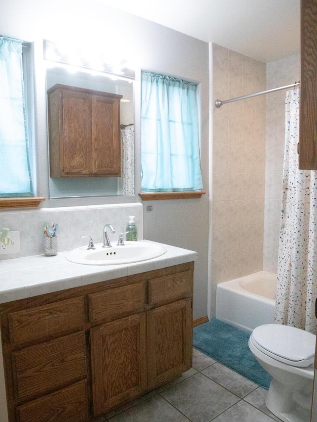 full bathroom with toilet, vanity, shower / bath combo with shower curtain, tile patterned flooring, and decorative backsplash