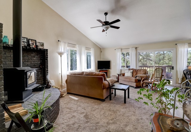 living area with ceiling fan, carpet floors, high vaulted ceiling, and a wood stove