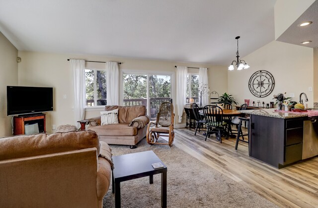 living area with lofted ceiling, light wood-style floors, a notable chandelier, and recessed lighting