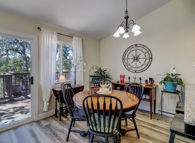 dining space featuring light wood-style floors, a chandelier, vaulted ceiling, and baseboards