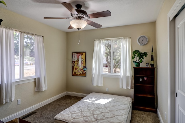 bedroom with dark colored carpet, multiple windows, a ceiling fan, and baseboards