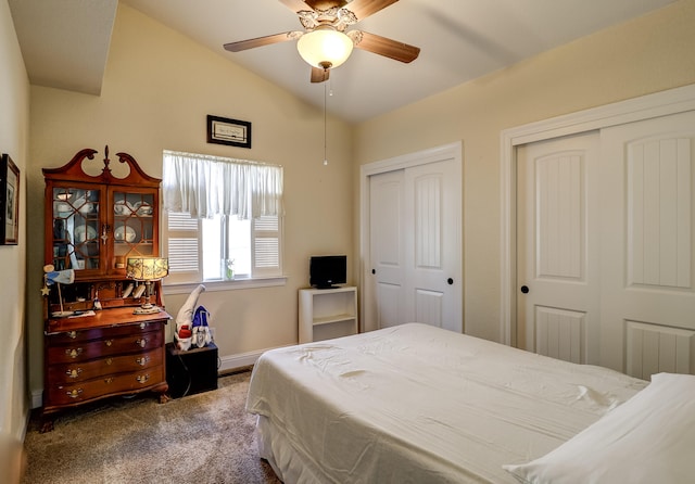 bedroom featuring ceiling fan, baseboards, vaulted ceiling, dark carpet, and two closets