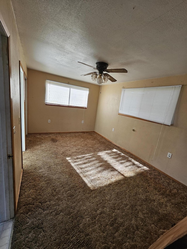 carpeted empty room with ceiling fan and a textured ceiling