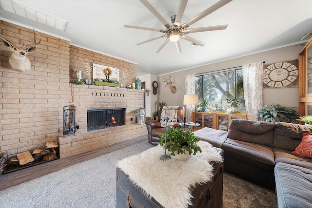 living room with ceiling fan, brick wall, wood-type flooring, and a fireplace