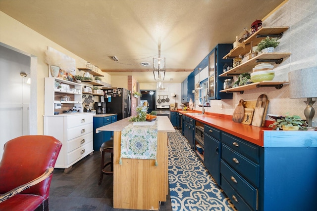 kitchen featuring blue cabinetry, a kitchen bar, black refrigerator, stainless steel fridge, and a kitchen island