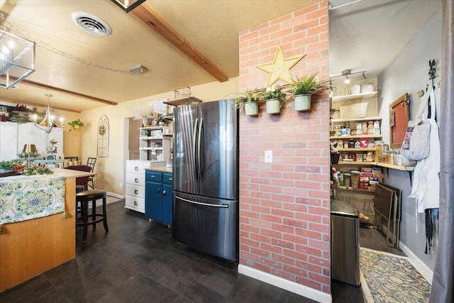 kitchen with blue cabinets, a textured ceiling, stainless steel refrigerator, a kitchen breakfast bar, and beamed ceiling