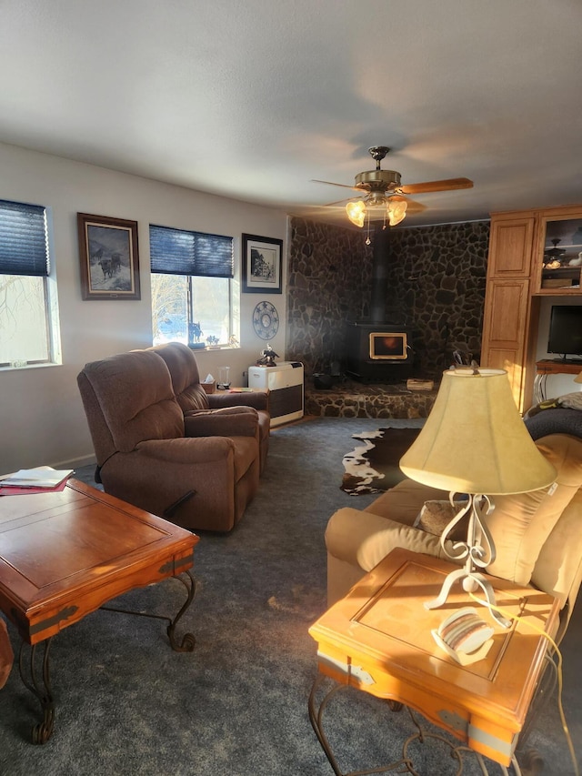 living room featuring dark colored carpet, a wood stove, and ceiling fan