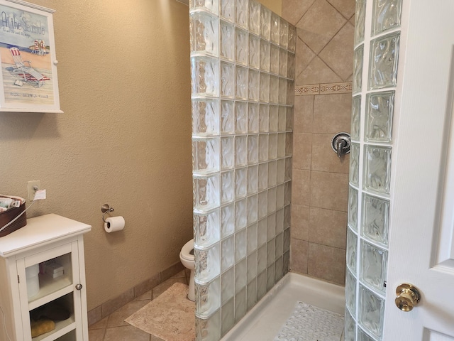 bathroom with tile patterned flooring, tiled shower, and toilet