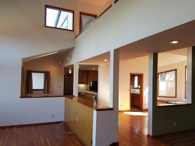 corridor with a towering ceiling and dark hardwood / wood-style floors