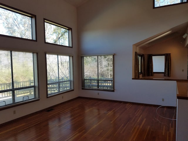 unfurnished living room featuring dark wood-type flooring and high vaulted ceiling