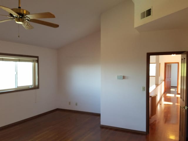 spare room with dark wood-type flooring, ceiling fan, and vaulted ceiling