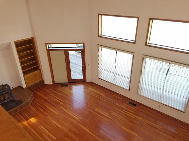 unfurnished living room with dark hardwood / wood-style flooring, a towering ceiling, and a wood stove