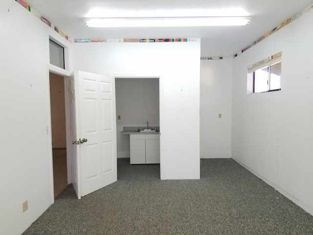 unfurnished bedroom with dark colored carpet and sink