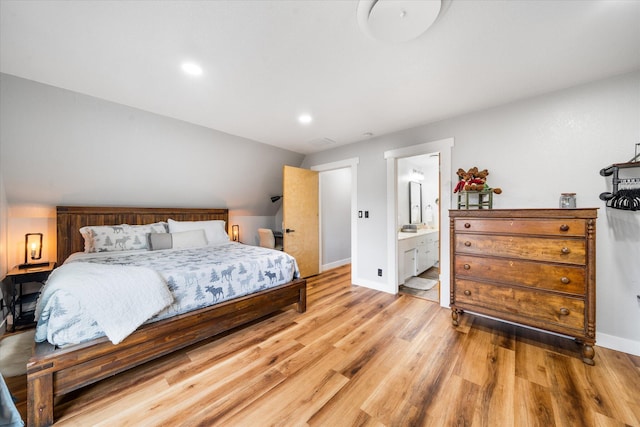 bedroom with ensuite bath and light wood-type flooring