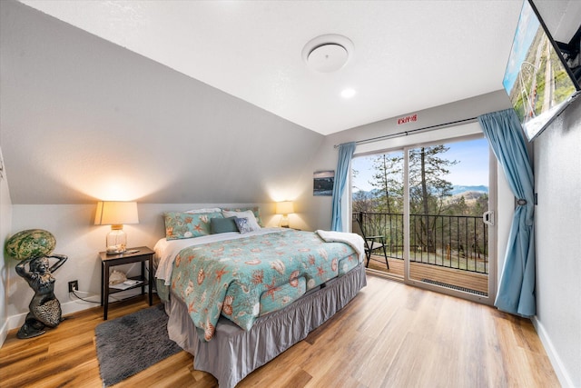 bedroom with hardwood / wood-style flooring, vaulted ceiling, and access to outside