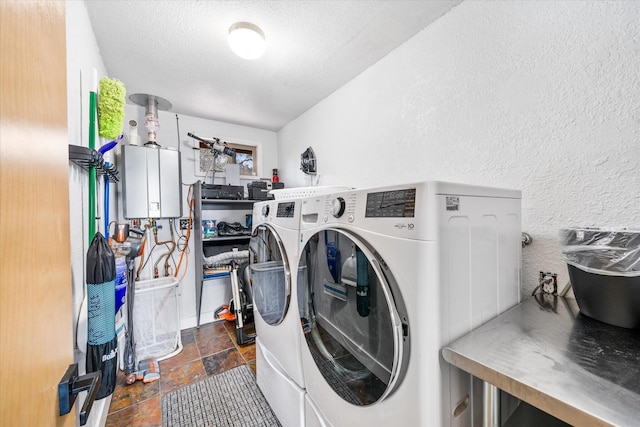 clothes washing area featuring water heater, washer and clothes dryer, and a textured ceiling