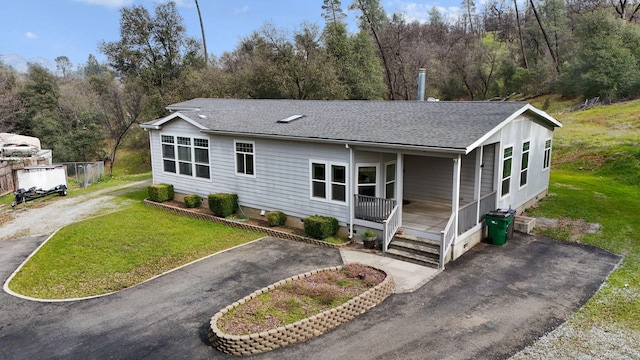 view of front of house with aphalt driveway, a porch, a shingled roof, and a front lawn