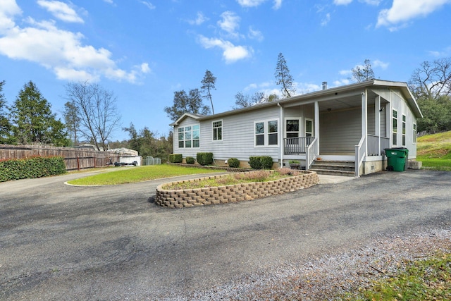 back of house with an attached carport, fence, a porch, a lawn, and driveway