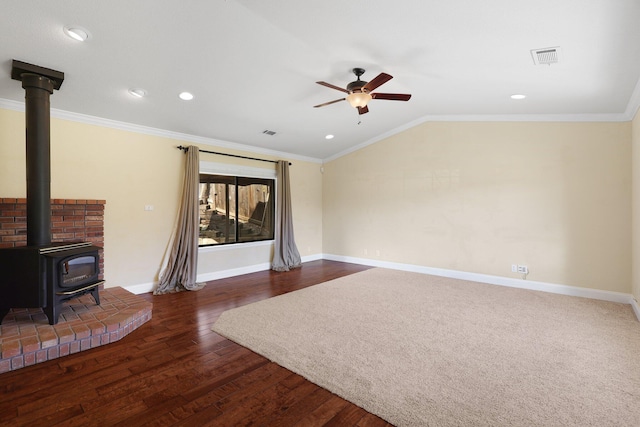 unfurnished living room featuring crown molding, lofted ceiling, and a wood stove