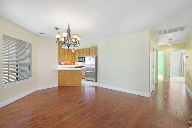 kitchen with wood-type flooring, an inviting chandelier, stainless steel refrigerator, and decorative light fixtures