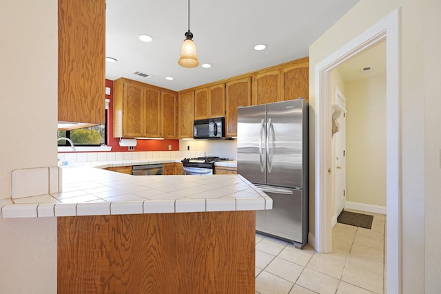 kitchen featuring light tile patterned floors, appliances with stainless steel finishes, tile counters, decorative light fixtures, and kitchen peninsula