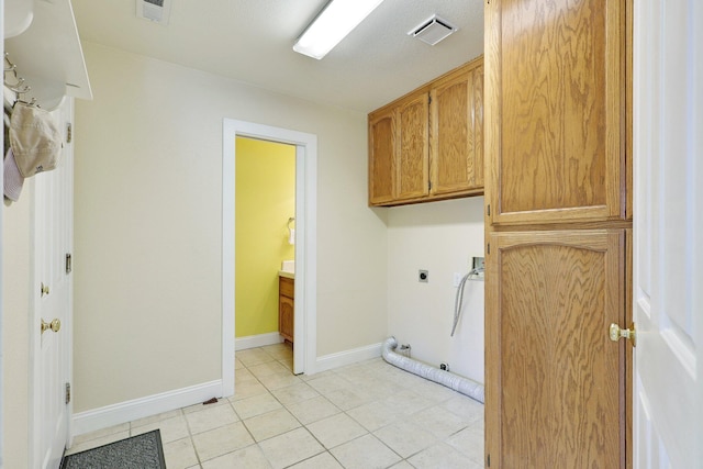 clothes washing area with gas dryer hookup, electric dryer hookup, light tile patterned floors, and cabinets