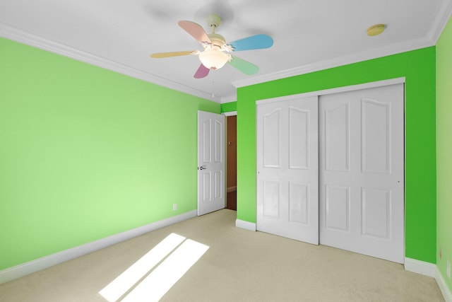 unfurnished bedroom featuring crown molding, light colored carpet, ceiling fan, and a closet