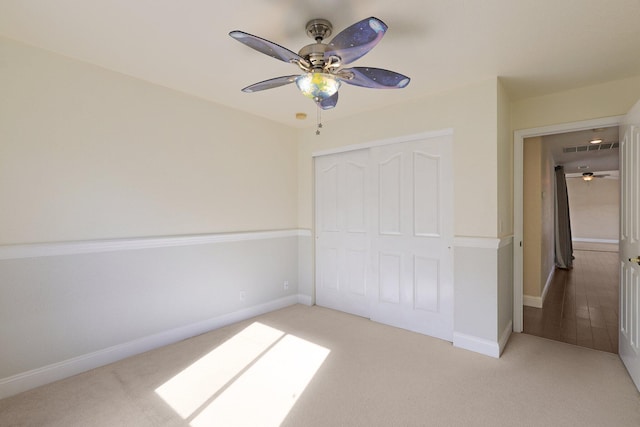 unfurnished bedroom featuring light carpet, ceiling fan, and a closet