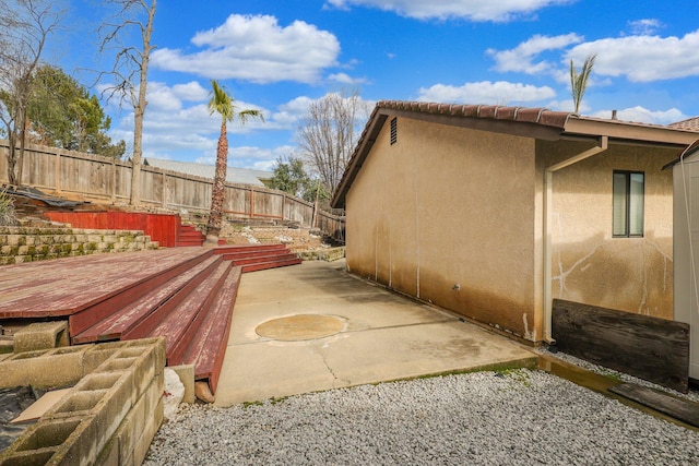 view of home's exterior featuring a wooden deck and a patio