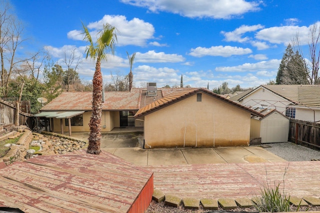 back of house with a patio, a deck, and a storage shed