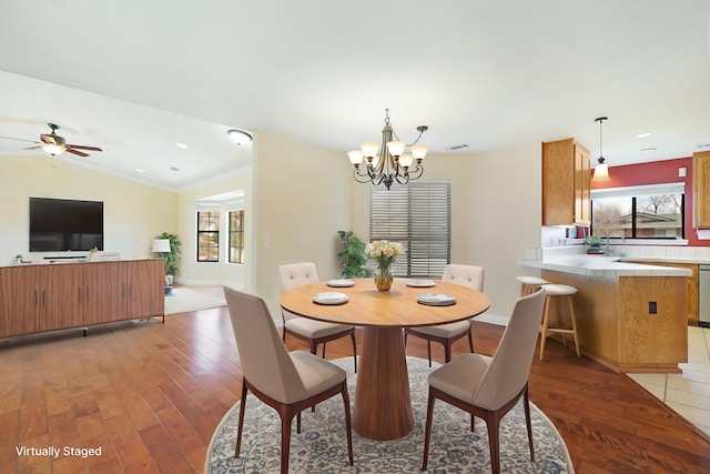 dining area featuring lofted ceiling, ceiling fan with notable chandelier, wood-type flooring, and ornamental molding