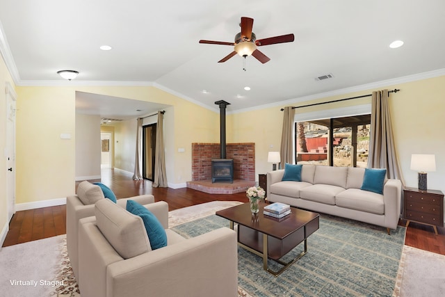 living room featuring lofted ceiling, crown molding, a wood stove, dark hardwood / wood-style flooring, and ceiling fan