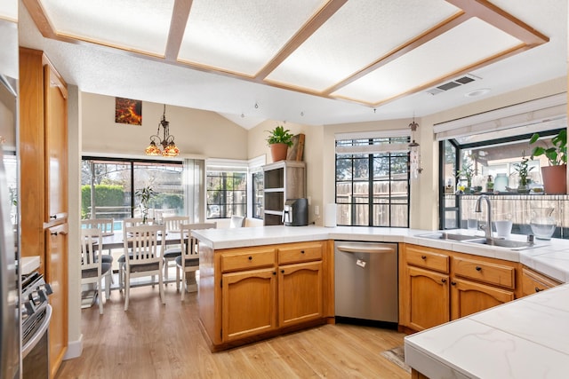 kitchen featuring appliances with stainless steel finishes, sink, hanging light fixtures, light hardwood / wood-style floors, and kitchen peninsula