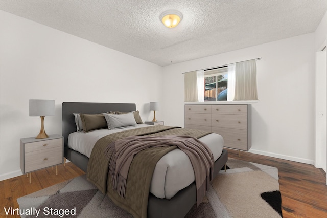 bedroom with a textured ceiling and dark hardwood / wood-style flooring