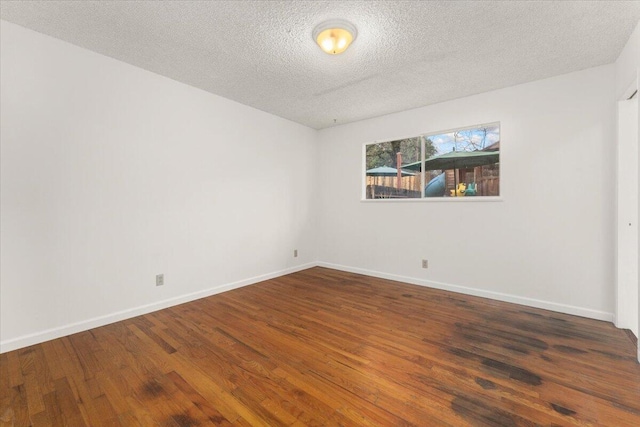 spare room featuring dark wood-type flooring and a textured ceiling