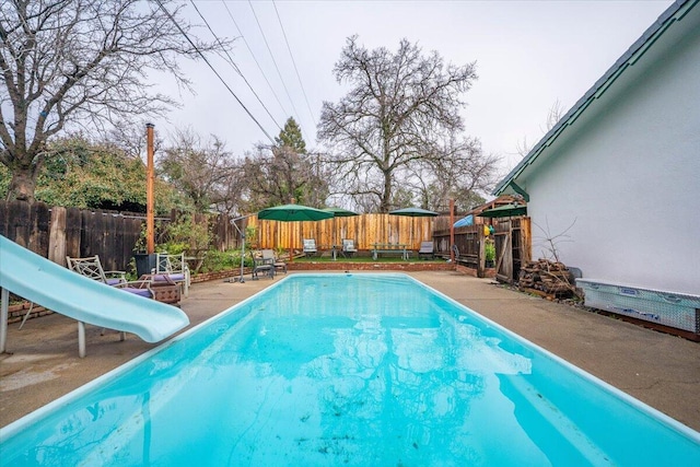 view of pool with a water slide and a patio