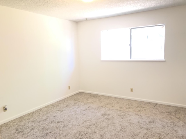 unfurnished room with a textured ceiling, carpet flooring, and baseboards