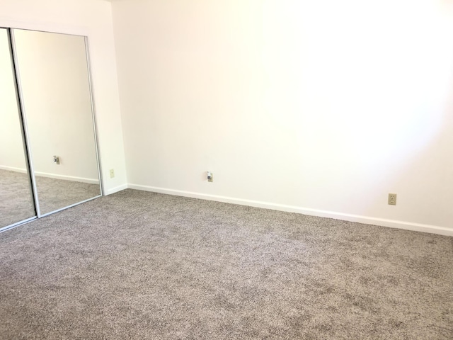 unfurnished bedroom with carpet floors, a closet, and baseboards