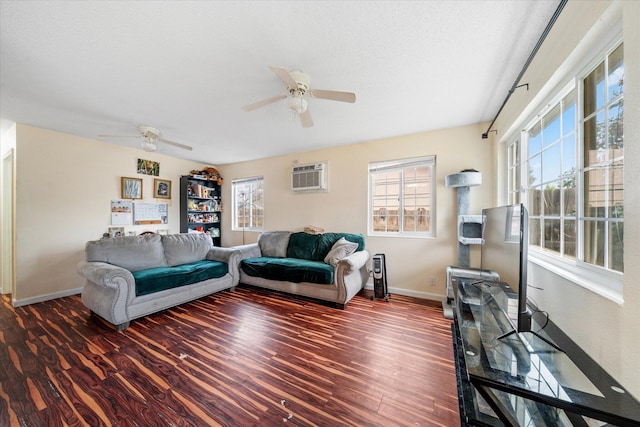 living area with a textured ceiling, ceiling fan, dark wood-type flooring, baseboards, and an AC wall unit