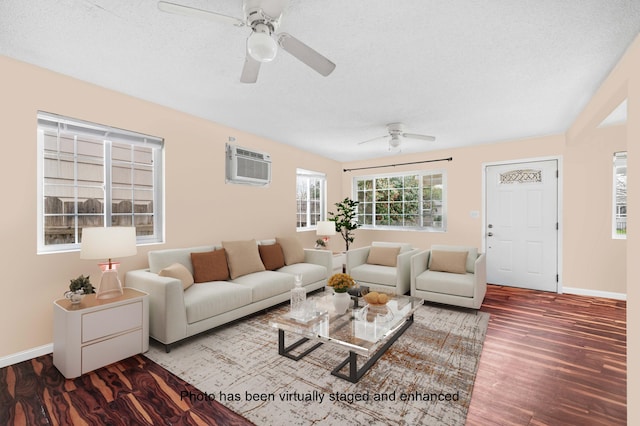 living area with a textured ceiling, a wall mounted air conditioner, wood finished floors, and baseboards