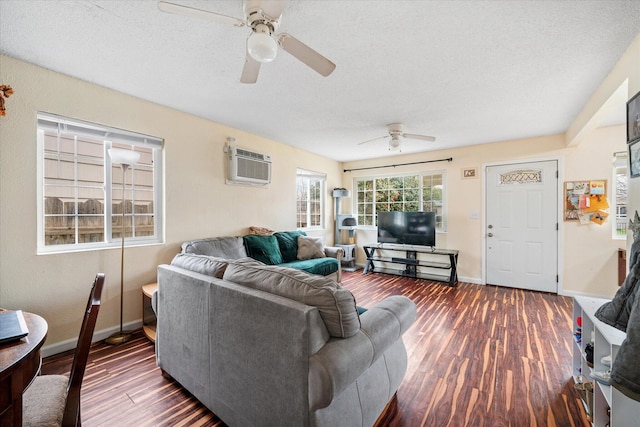 living area with dark wood-style floors, a ceiling fan, an AC wall unit, a textured ceiling, and baseboards