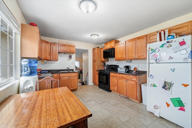 kitchen with a sink, backsplash, brown cabinets, black appliances, and dark countertops