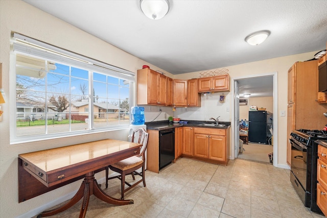 kitchen with dark countertops, black appliances, baseboards, and a sink