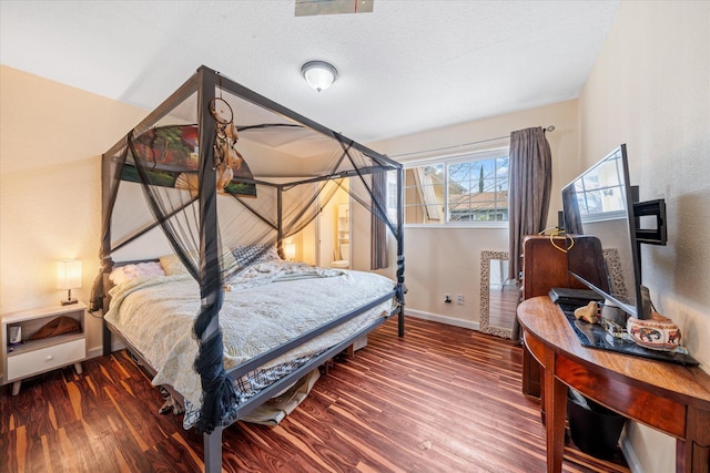 bedroom featuring a textured ceiling, dark wood-style flooring, and baseboards