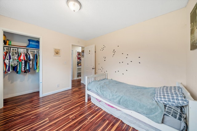 bedroom with a closet, baseboards, and dark wood-type flooring