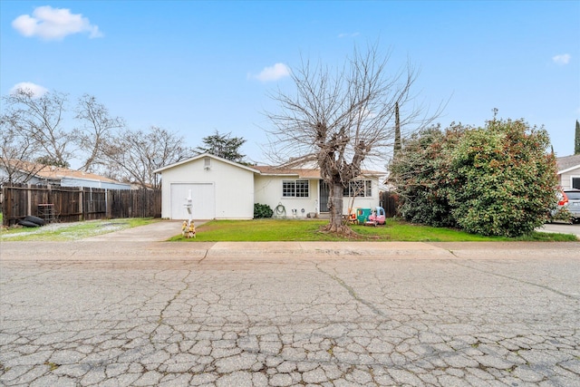 view of front of property featuring an attached garage, fence, driveway, and a front lawn