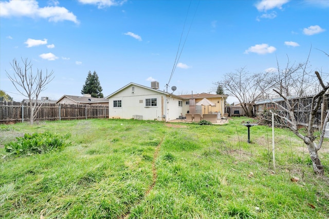 rear view of house with a fenced backyard, a yard, a wooden deck, and stucco siding