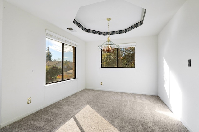 empty room with carpet, a raised ceiling, visible vents, and baseboards