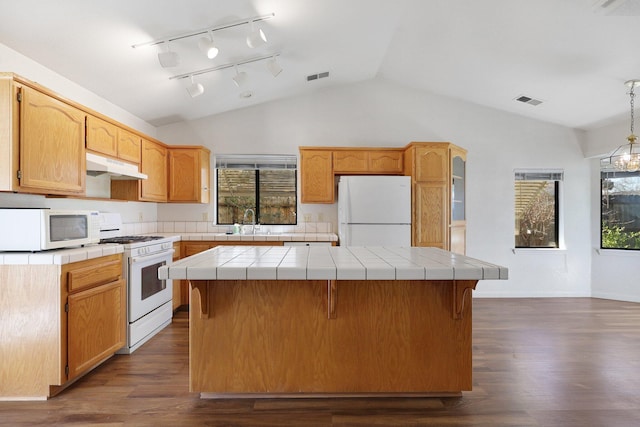 kitchen with tile countertops, under cabinet range hood, white appliances, a kitchen island, and visible vents