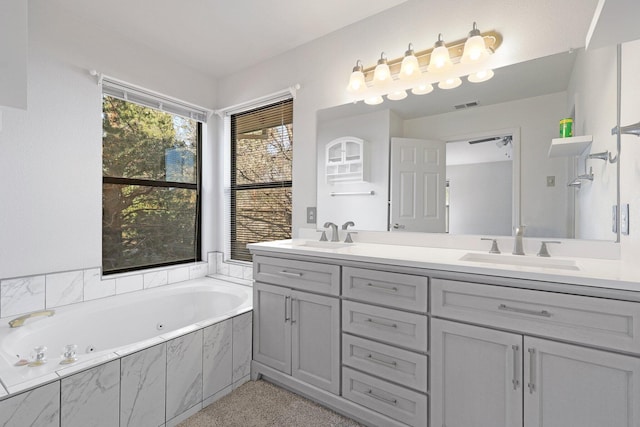 full bathroom featuring double vanity, a tub with jets, visible vents, and a sink